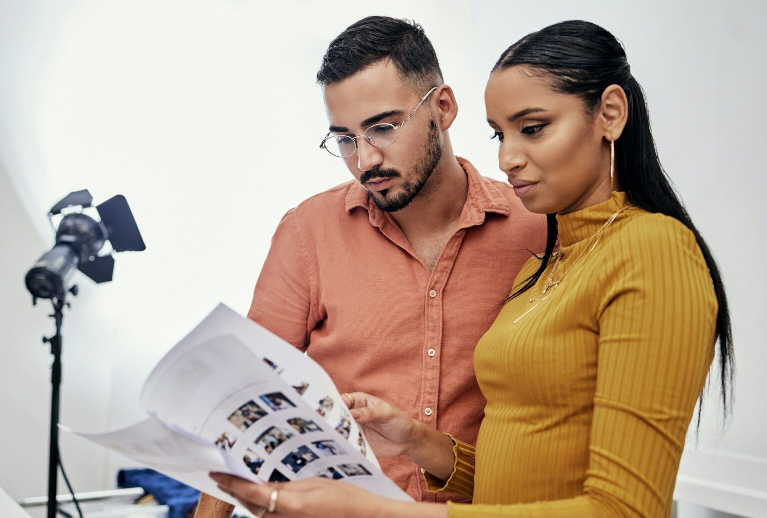 Documents, teamwork or planning with a photographer and model talking in a studio for creative prod